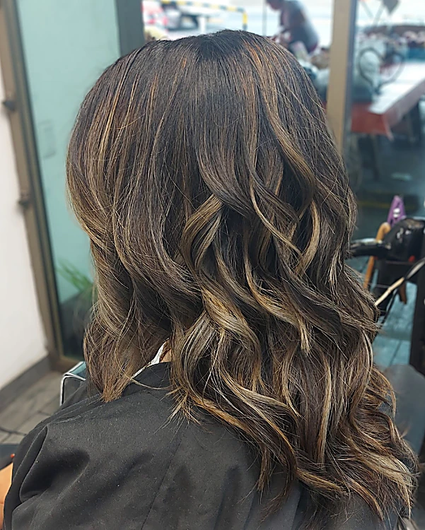Cabello largo castaño en ondas con luces claras, visto de espaldas en el salón