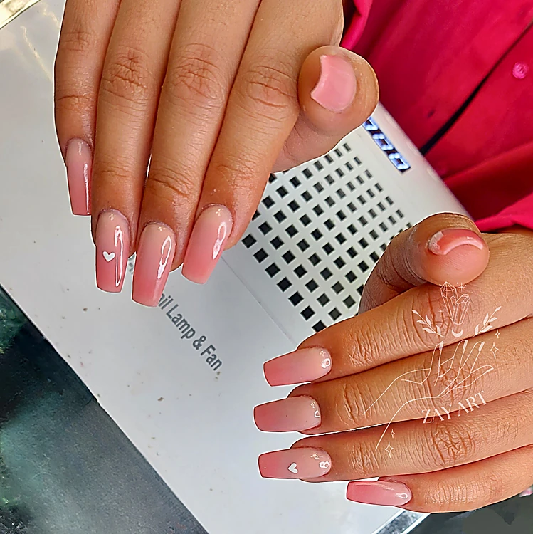 Uñas largas en rosa degradado con corazones blancos pequeños